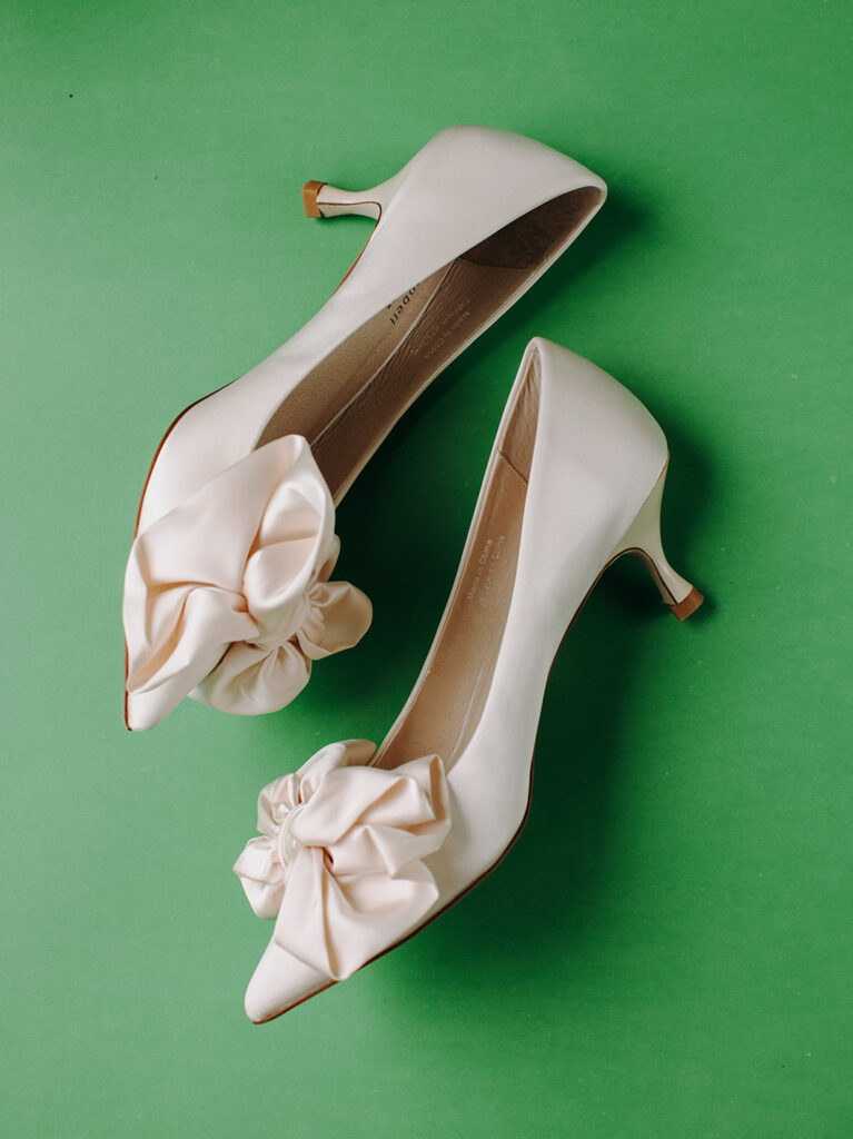 green flat lay background with brides shoes on top